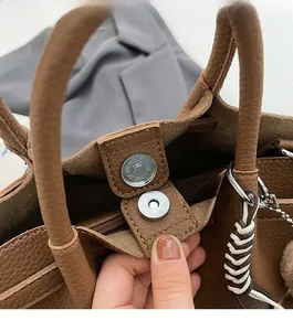 Gros plan du fermoir magnétique et de l'intérieur en cuir texturé d'un sac seau marron