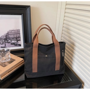 Detailed close-up of a canvas tote bag featuring a front buckle pocket and side zipper