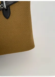 Macro detail of brown twill fabric with black leather strap and silver metal buckle