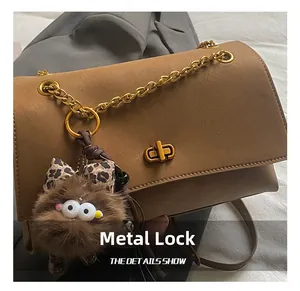 Detail of premium golden rotary hardware lock on brown leather shoulder bag with chain