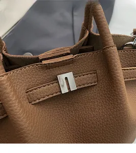 Gros plan des coutures fines et du cuir grainé sur un sac seau marron foncé élégant