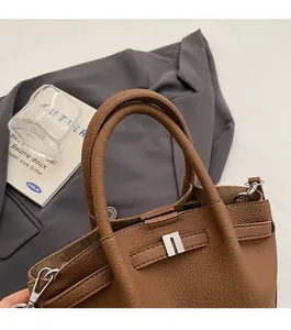 Détail du sac à main en cuir marron grainé avec boucle métallique et anses arrondies