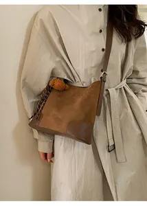 Détail du sac seau en daim marron avec glands à cordon et accessoire en peluche