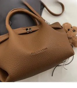 Détail d'un sac en cuir litchi marron avec fermoir rotatif argenté et bijou d'ours