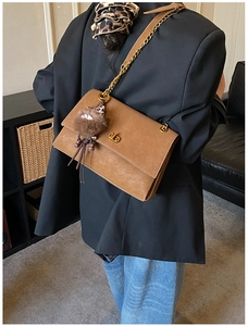 Detail of retro brown leather shoulder bag with gold twist lock and plush doll charm