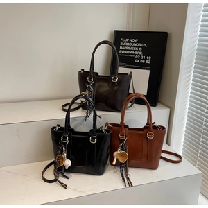 Three bucket tote bags in black, dark brown, and tan with baseball charms on display