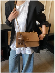 Detail of brown suede crossbody bag with gold D-buckle and cute owl plush keychain