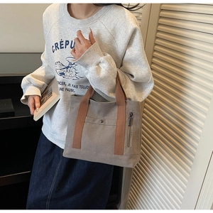 Detail of taupe canvas tote bag with brown handles and snap button pocket for daily commute