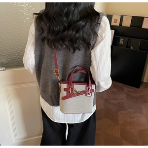 Detail of vintage canvas and burgundy leather bucket bag with golden metal lock buckle