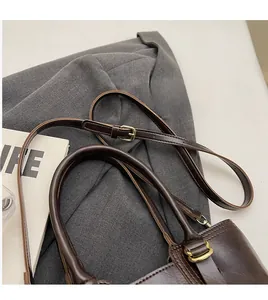 Close-up of dark brown bucket bag with adjustable shoulder strap and gold hardware