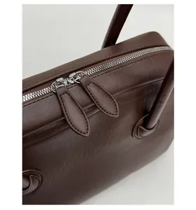 Detail of smooth double zippers and lychee grain leather on dark brown shoulder bag