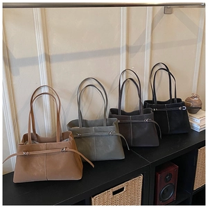 Detail of four retro tote bags in suede finish with contrast stitching on display shelf