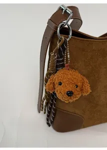 Détail d'un charm en peluche marron avec cordons sur un sac cabas en daim élégant