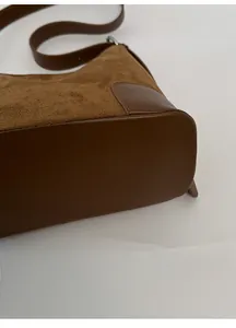 Détail de la base large d'un sac cabas en daim marron montrant sa structure robuste