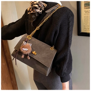 Detail of dark grey suede tote bag with gold chain strap and leopard print plush charm