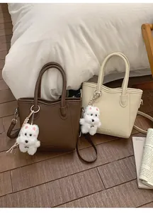 Detailed view of structured faux leather tote bags in brown and beige with plush charms