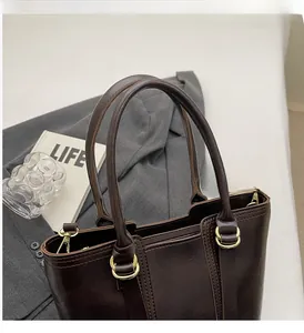 Detail of dark brown tote bag showing leather texture and gold metal ring hardware