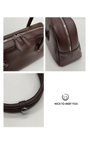 Detail of dark brown leather tote featuring double metal zippers and padded handles