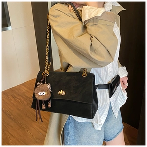 Detail of black suede flap bag with gold chain strap and playful eye plush charm