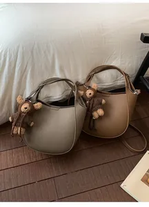 Detail of grey-green and caramel brown pebbled leather bucket bags with teddy bear charms