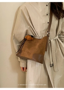 Détail du sac seau en daim caramel avec bandoulière réglable et accessoire d'ours en peluche