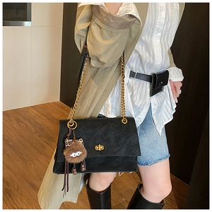 Chic black suede shoulder bag with gold chain strap and cute fuzzy monster charm