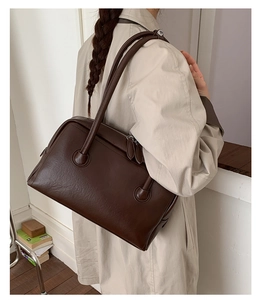 Detail of a dark brown vintage Boston bag in soft matte leather shown on a shoulder
