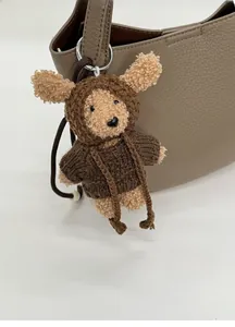 Detail of a handmade knitted bear charm with a metal ring attached to a lychee leather bag