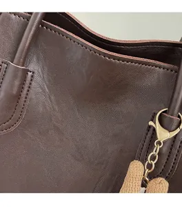 Close-up of deep brown leather tote with gold foil stamped brand logo and metal hardware
