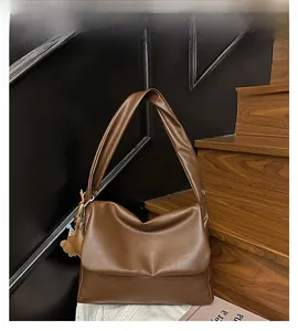 Detail of a dark brown slouchy hobo bag with star charms on a wooden staircase