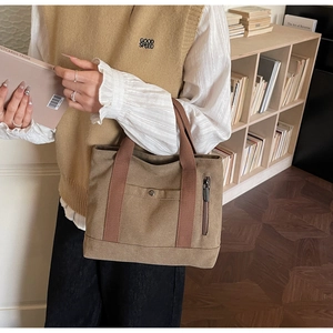 Detailed view of a vintage brown canvas tote bag with snap pockets and functional side zippers