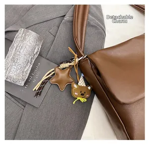 Close-up of a dark coffee oil wax leather tote bag with a removable star and bear pendant