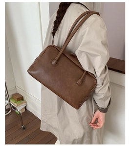 Detail of dark brown vintage Boston bag with fine leather texture and long straps