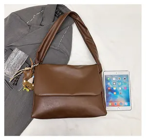 Flat lay of brown oil wax leather tote bag with cute bear charm and daily essentials