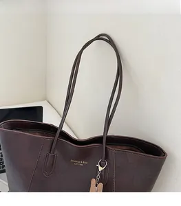 Detail of dark brown tote bag showing gold logo and thin shoulder straps for comfort