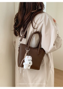 Gros plan d'un sac seau en cuir marron grainé avec un petit pendentif chien en peluche