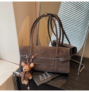 Macro detail of vintage brown faux suede tote bag with decorative bear pendant accessory