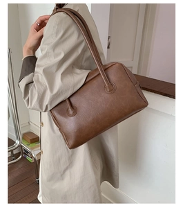 Detail of vintage brown leather texture and stitching on minimalist Boston shoulder bag