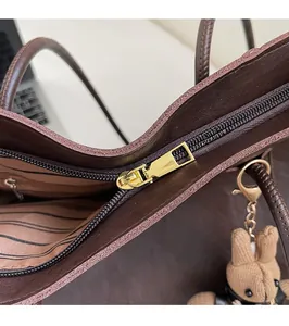 Close-up of smooth gold zipper and brown striped lining on a large tote bag