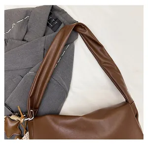 Detail of dark brown oil wax leather tote bag with star pendant on a grey blazer