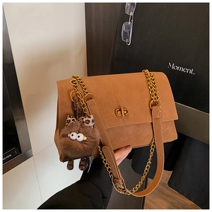 Brown leather tote with gold chain strap, twist lock, and cute plush charm detail