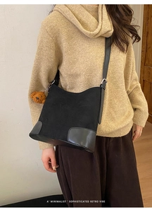 Détail du sac seau rétro en daim noir avec bandoulière réglable et breloque petit ours