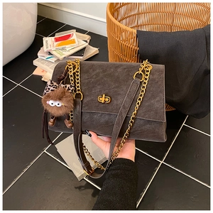 Detailed close-up of dark grey suede bag with golden twist lock and plush monster charm