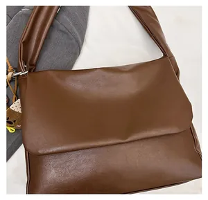 Close-up of deep brown oiled leather tote bag with flap closure and cute bear pendant