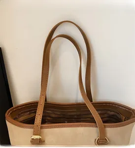 Detail of adjustable leather strap and striped lining on an apricot tote bag