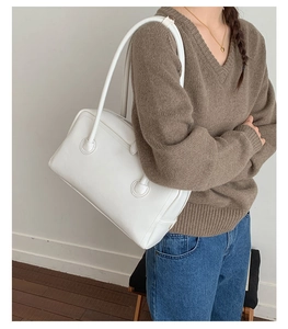 Detailed side view of white faux leather tote bag worn by model for daily commute