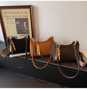 Detalle de bolsos media luna con correas tejidas y colgantes de cuentas de madera