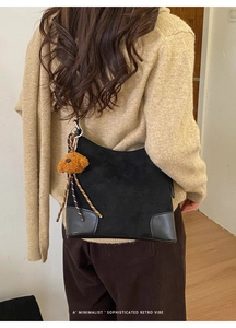 Détail du sac croissant en daim noir avec un joli pendentif chien en peluche