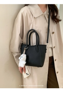 Detail of black litchi pattern tote bag with teddy charm and adjustable strap