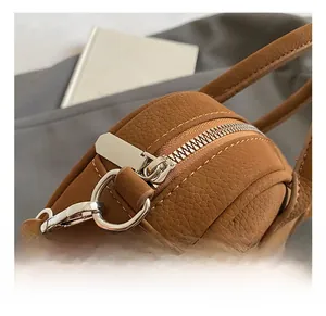 Close-up of silver metal zipper and hardware on brown lychee texture leather bag